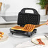 Black waffle maker with cooked waffles on kitchen counter