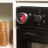 Kitchen timer with red dial attached to oven control panel, shown in use.