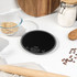 Black digital kitchen scale on worktop with baking ingredients, round shape, UK model