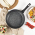 Set of black speckled non-stick saucepans and frying pans with glass lids on kitchen counter