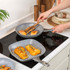 Grey non-stick frying and grill pans on electric hob cooking salmon and hasselback squash