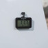 Black digital fridge thermometer attached to white appliance, temperature display visible