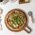 Stone-baked pizza with mozzarella and rocket on wooden board, top-down view