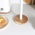 Wood and white paper towel holder on kitchen counter next to toaster and buttered toast