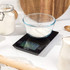 Digital kitchen scale with glass bowl of flour in a baking setting