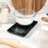 Digital kitchen scale with glass bowl of flour in a baking setting