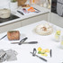 White chopping boards with knives, roast joint, and citrus fruit on modern kitchen counter