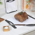 White chopping boards with knives, roast joint, and citrus fruit on modern kitchen counter