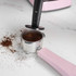 Pink espresso coffee machine making a fresh espresso into a glass cup.