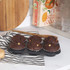 Six chocolate muffins with white chocolate chips in a tin on a kitchen countertop.