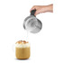 Milk frothing jug pouring steamed milk into cappuccino with foam and cocoa topping
