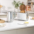 Grey handled electric kettle pouring hot water into a dark mug, product in use