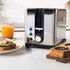 Stainless steel two-slice toaster with seeded bread inside, angled view.