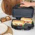 Panini press open with two toasted sandwiches inside, showing ingredients.