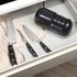 Electric knife sharpener and black-handled kitchen knife on white countertop