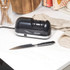 Electric knife sharpener and black-handled kitchen knife on white countertop
