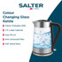 Glass electric kettle with silver accents being filled with water at a kitchen sink