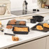 Set of black non-stick baking trays and tins on kitchen worktop with baked goods