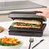 Electric grill with cooked steak and seasoned orange vegetables on the grill plate