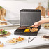 Black panini press with two toasted sandwiches shown inside
