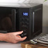Black microwave oven on kitchen counter with sliced bread and soup.