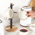 Set of cream ceramic mugs with brown rim on wooden stand, next to white kettle