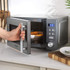 Silver microwave oven with digital display, timer set to 5 minutes, hand turning control knob