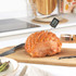 Digital cooking thermometer measuring roast ham temperature on kitchen counter