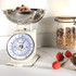 Mechanical kitchen scale with bowl containing granola and berries on countertop