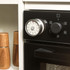 Stainless steel mechanical kitchen timer attached to oven, side view