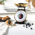 Broken dark chocolate pieces on a gold metal kitchen scale bowl