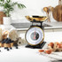 Black mechanical kitchen scale with gold bowl, shown side-on