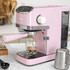 Pink microwave oven with digital display, shown on a kitchen counter with cooked food