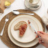 Table setting with cream stoneware plate, woven placemat, linen napkin and silver cutlery