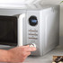 Hand setting timer on grey microwave oven in kitchen