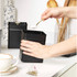 Hand adding sugar to black metal storage canister on kitchen counter