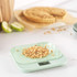 Digital kitchen scale in pastel green weighing crumble topping, pie and apples in background