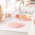 Pink digital kitchen scale on countertop with baking ingredients and Battenberg cake