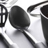 Close-up of black serving spoon and utensils next to saucepan, shown for kitchenware listing.