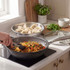 Non-stick silver frying pan cooking noodles, Salter brand, with glass lid on kitchen counter
