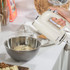 Cream hand mixer in use, mixing dough in a metal bowl on a kitchen counter