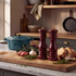 Red glossy wooden pepper mill showing ceramic grinder, angled side view