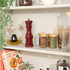 Red glossy wooden pepper mill showing ceramic grinder, angled side view
