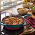 Green cast iron frying pan with chicken and vegetables cooking on hob, highlighting heat retention