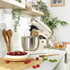 Cream stand mixer with stainless steel bowl and whisk attachment, angled side view.