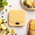Yellow Salter kitchen scale with cakes, lemons, and blueberries on marble surface