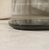 Black round digital bathroom scale on tiled floor, side profile view