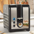 Black and chrome 2-slice toaster with reheat and defrost buttons, shown on kitchen counter