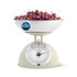 Cream mechanical kitchen scale with bowl of cherries, label reads no batteries needed