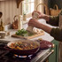 Cream pepper grinder seasoning stew in burgundy cast iron casserole on gas hob